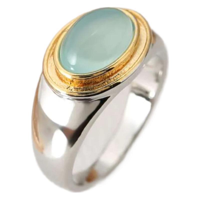 Ring with a green gemstone and gold and silver band on a white background