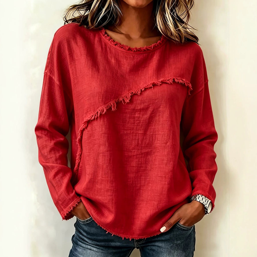 Person wearing a red frayed hem sweater against a plain background