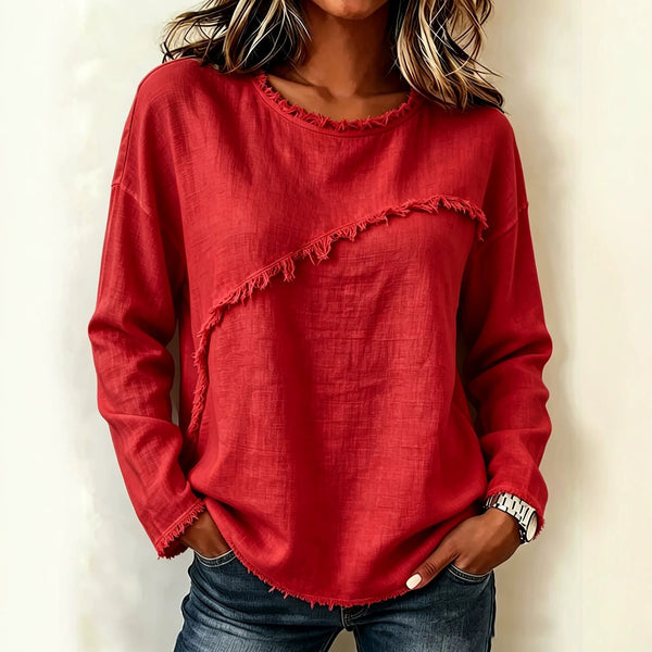 Person wearing a red frayed hem sweater against a plain background
