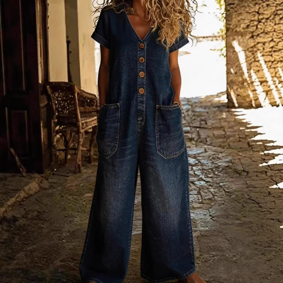 Person wearing a denim jumpsuit standing in a sunlit alleyway.