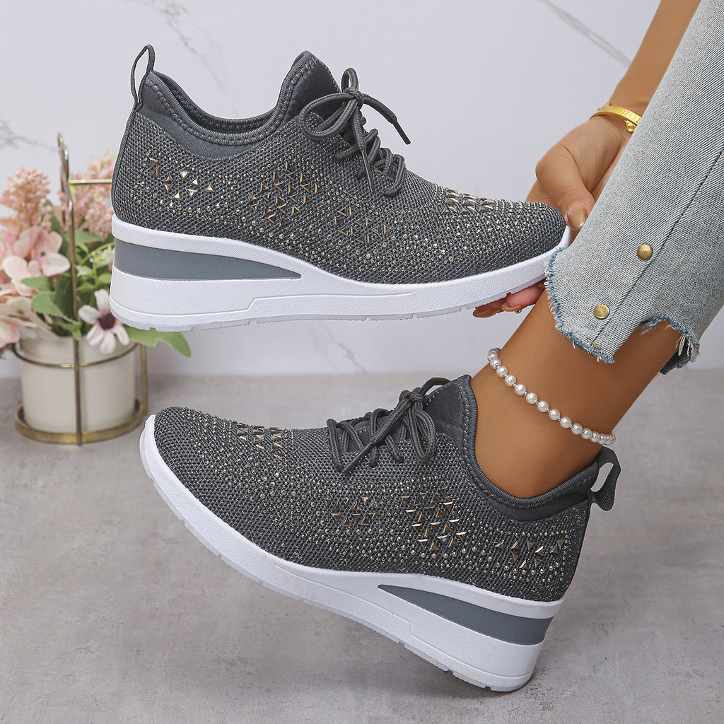 Gray sneakers with white soles worn by a person, with a blurred background