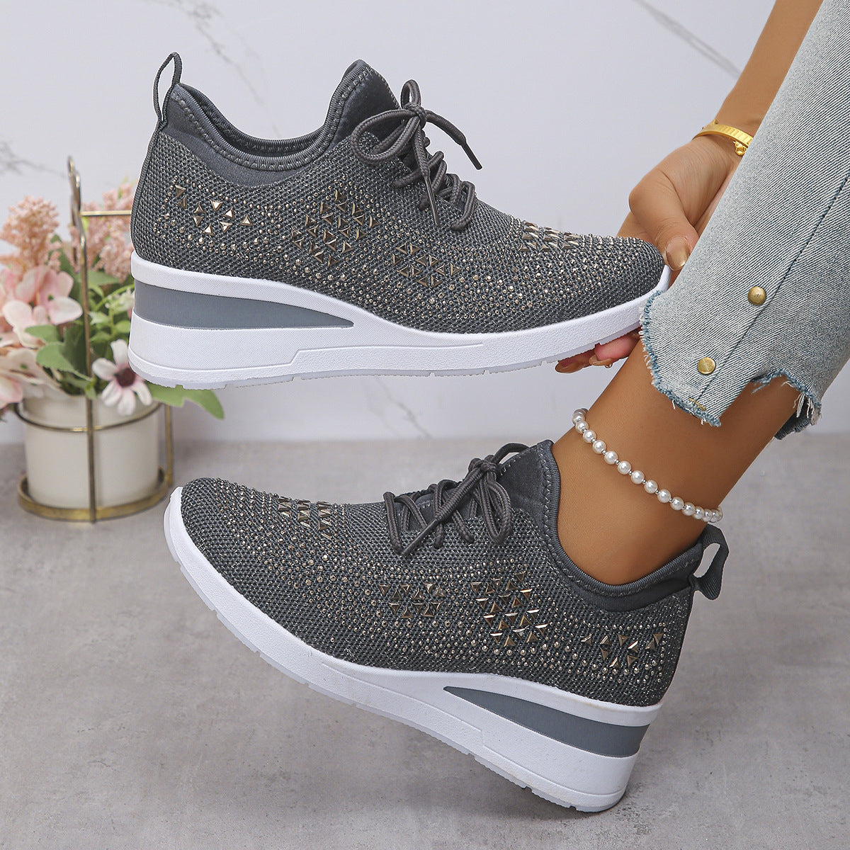 Gray sneakers with white soles worn by a person, with a blurred background