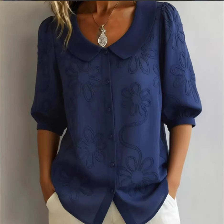 Navy blue blouse with floral patterns worn by a person against a neutral background