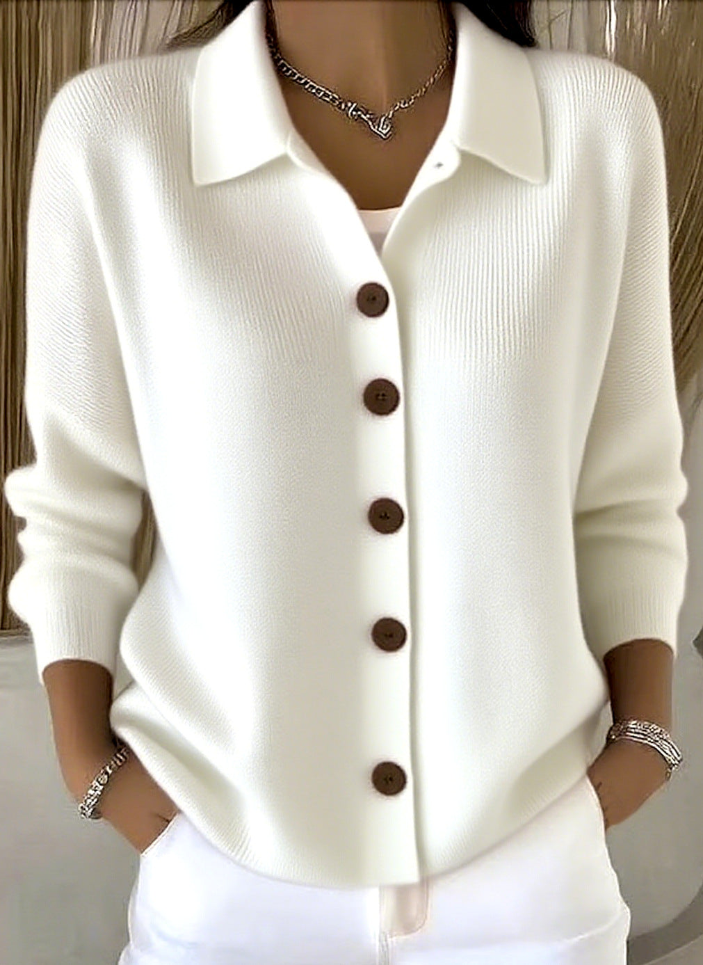 White button-up shirt with brown buttons worn by a person against a neutral background