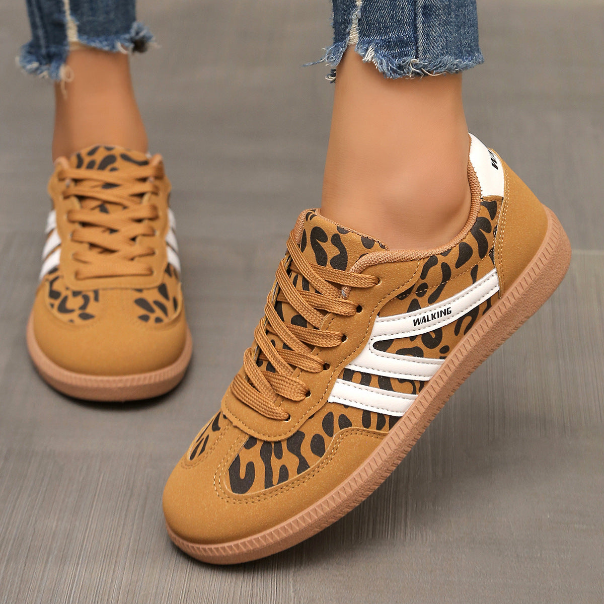 Brown sneakers with leopard print and white stripes worn by a person on a gray background