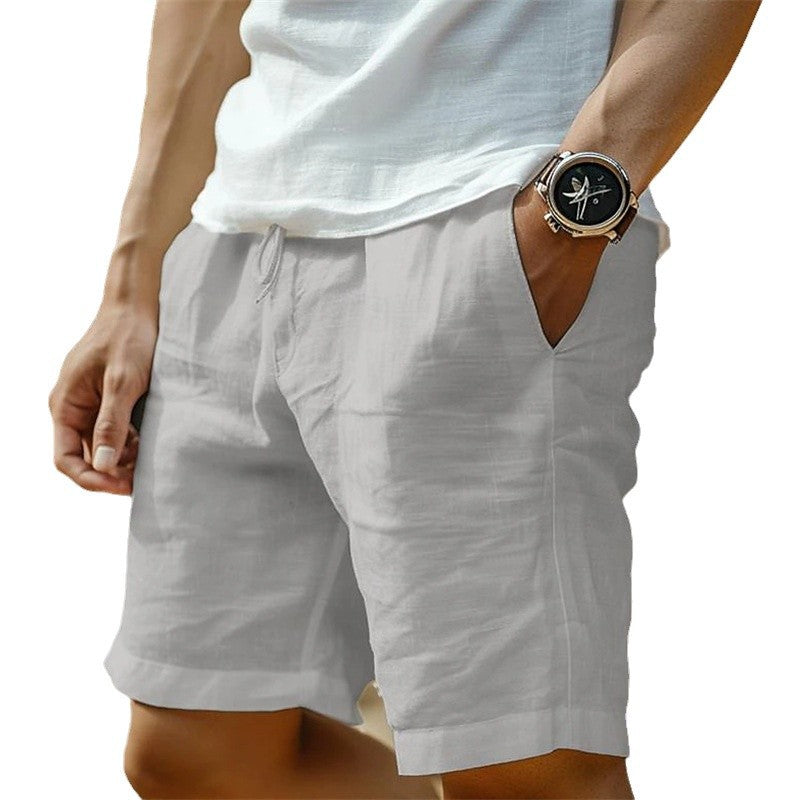 Person wearing light gray shorts with a white shirt and gold watch on a white background