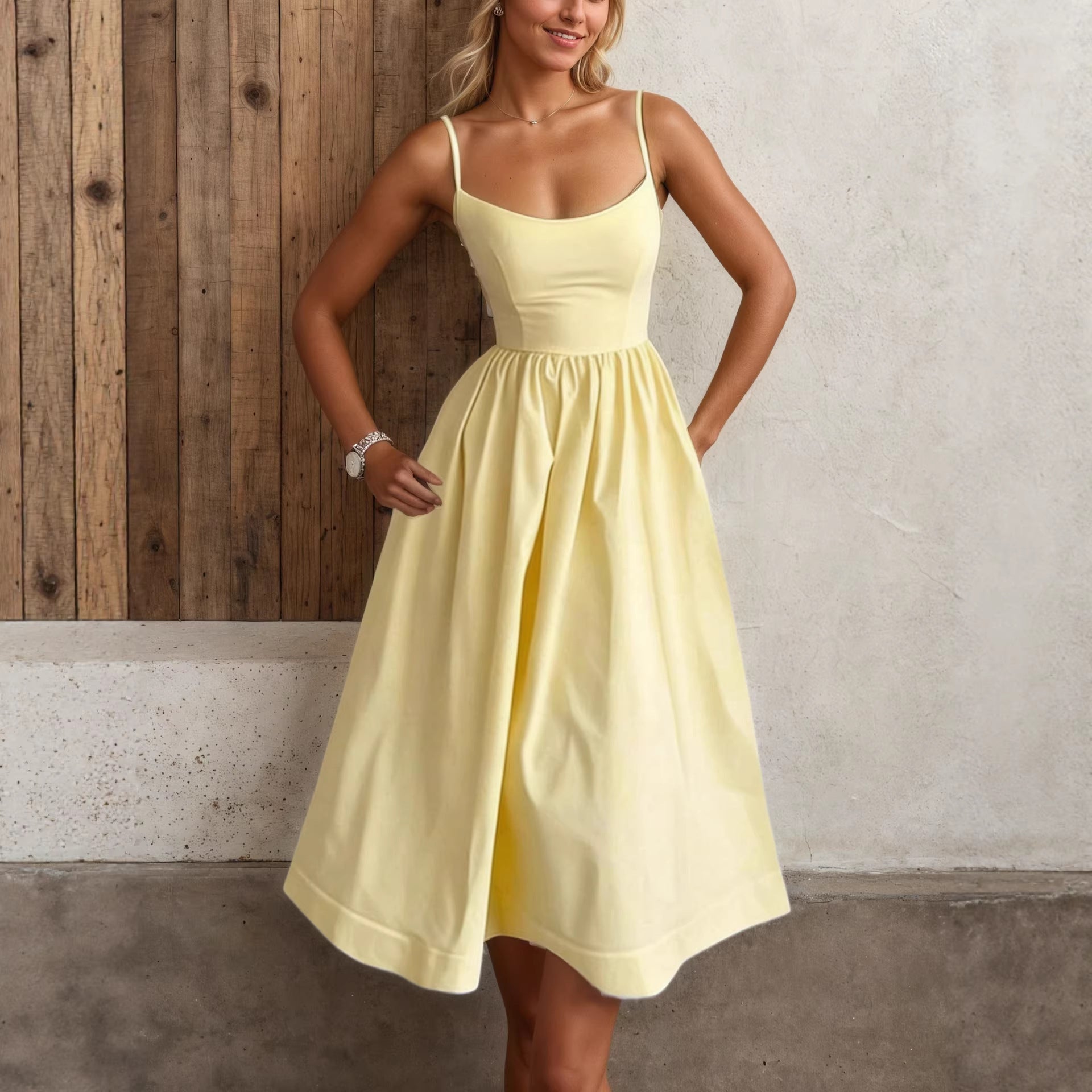 Woman wearing a yellow dress standing against a wooden and concrete wall.
