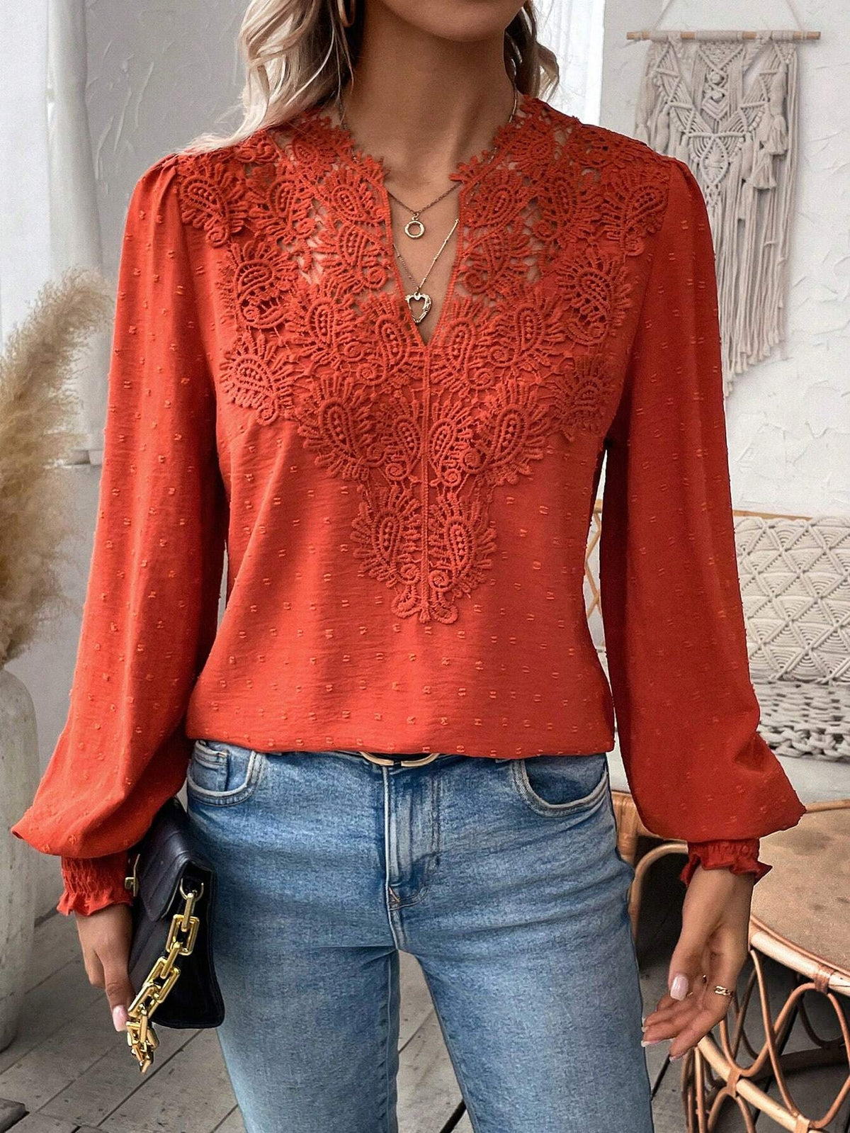 Person wearing a red lace top and blue jeans indoors.