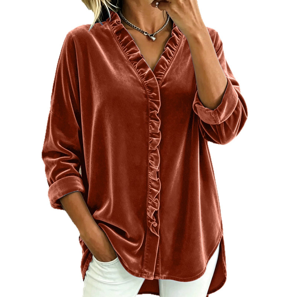 A woman wearing a rust-brown velvet long-sleeve blouse with a ruffled front placket and white pants, shown against a plain white background.