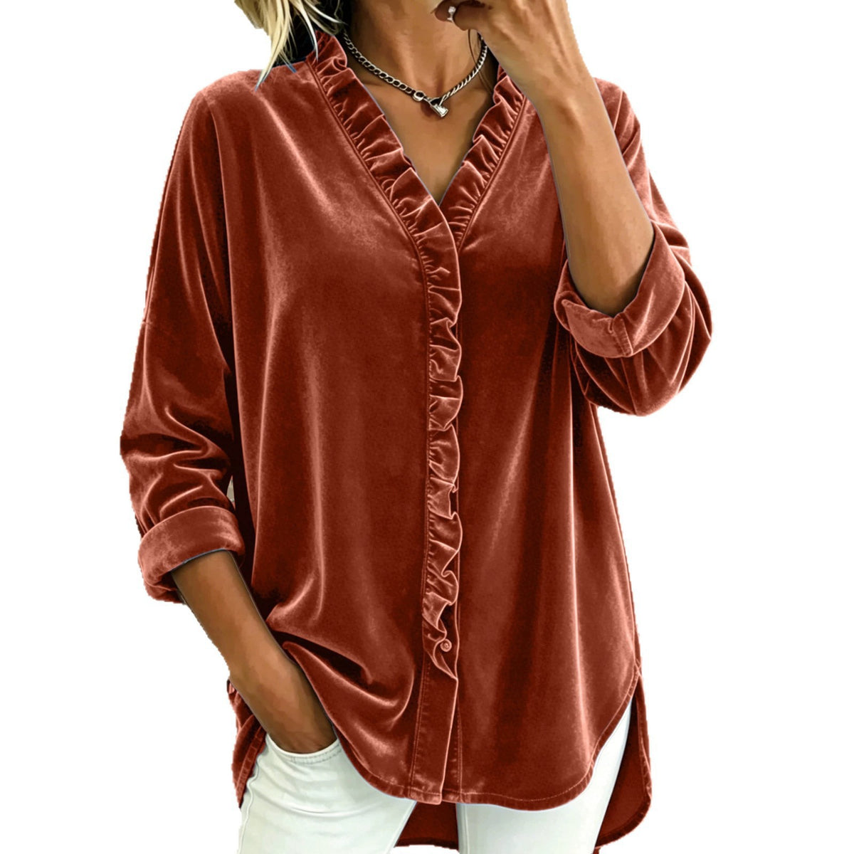 A woman wearing a rust-brown velvet long-sleeve blouse with a ruffled front placket and white pants, shown against a plain white background.