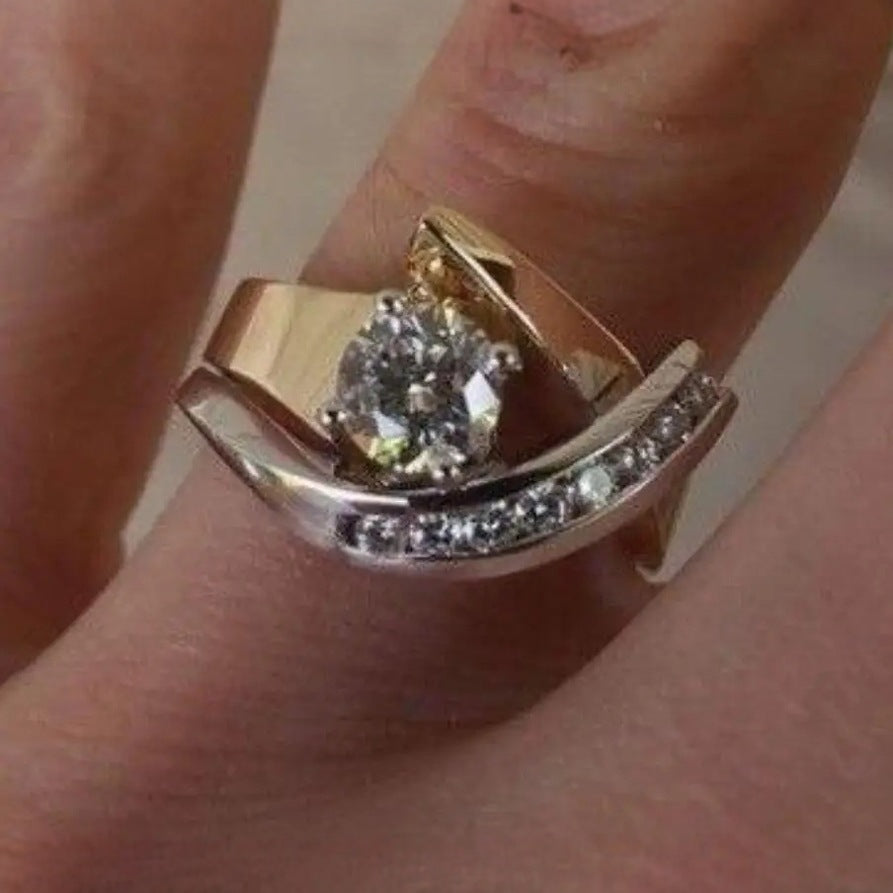 Gold ring with a diamond on a finger against a neutral background