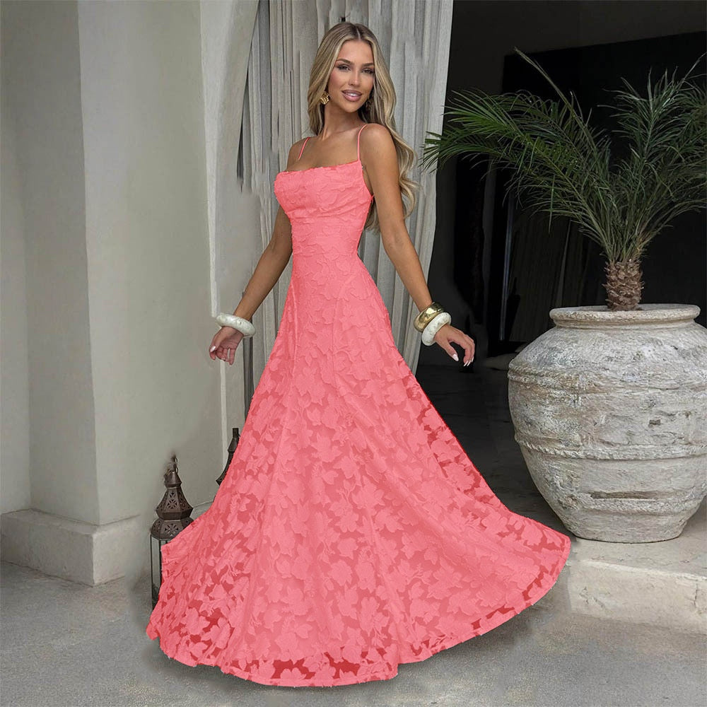 Woman in a pink lace dress standing in an indoor setting with a plant and lanterns.