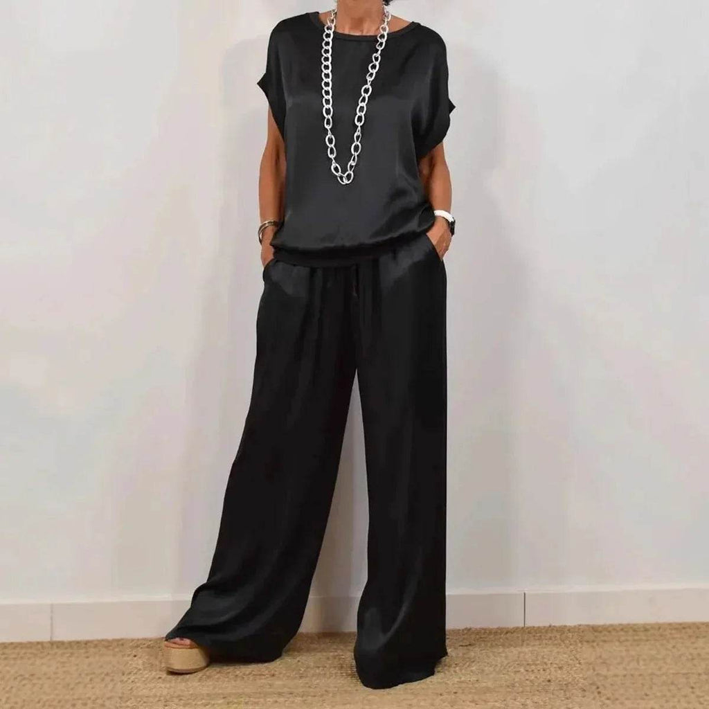 Woman modeling black satin wide-leg pants and top, styled with chunky chain necklace, ZA-Zola fashion