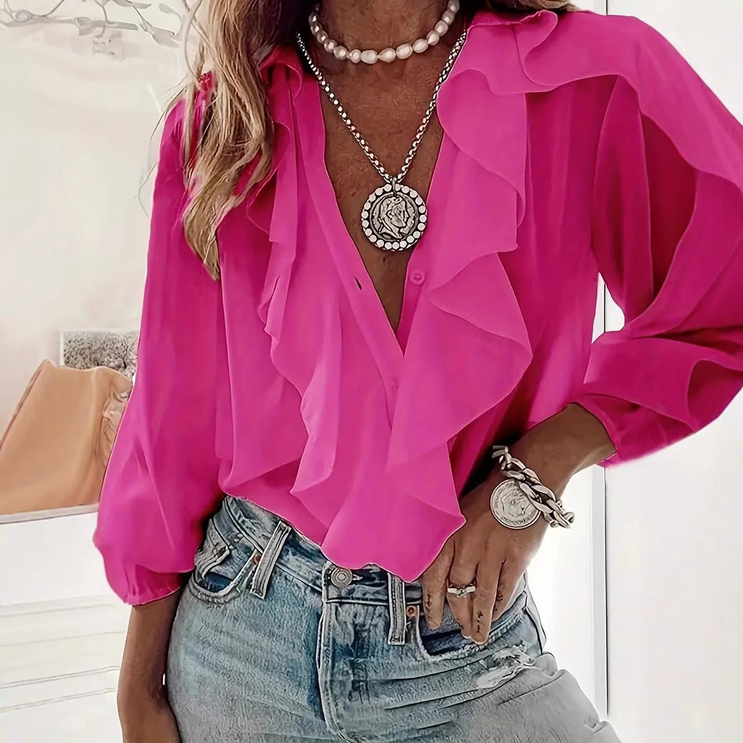Person wearing a bright pink blouse with ruffled details, denim jeans, and layered necklaces.