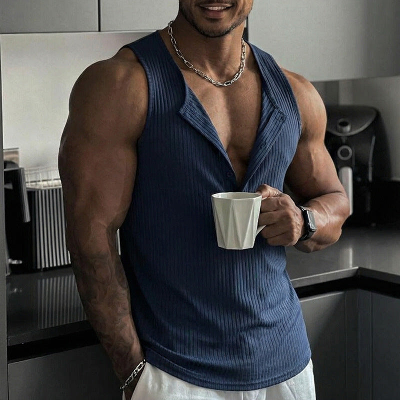 Man in a blue tank top holding a white mug in a kitchen.