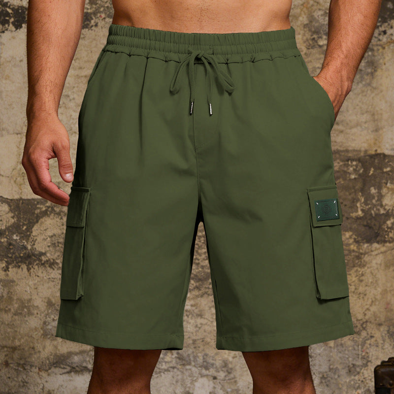 Green cargo shorts worn by a person against a textured wall background