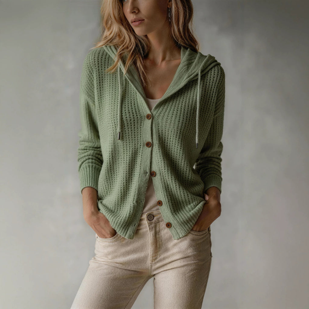 Woman wearing a green knitted cardigan with brown buttons against a neutral background