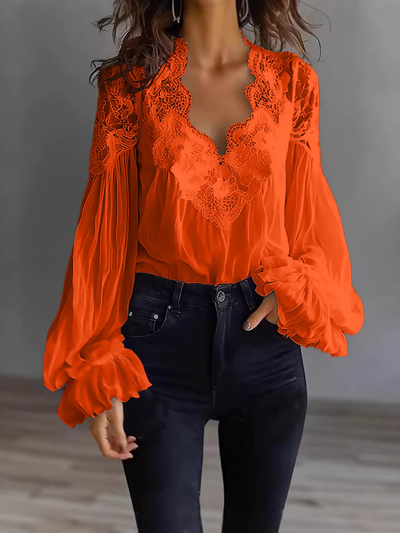 Orange lace top worn by a person against a neutral background