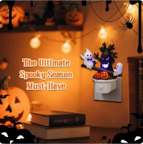 A Halloween-themed night light plug-in featuring a spooky tree with glowing purple eyes, two white ghosts, and jack-o'-lanterns, shown plugged into a wall outlet in a warmly lit Halloween room setting with promotional text.