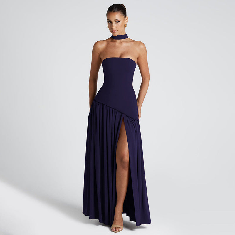 Woman wearing a strapless navy gown with a slit on a light gray background