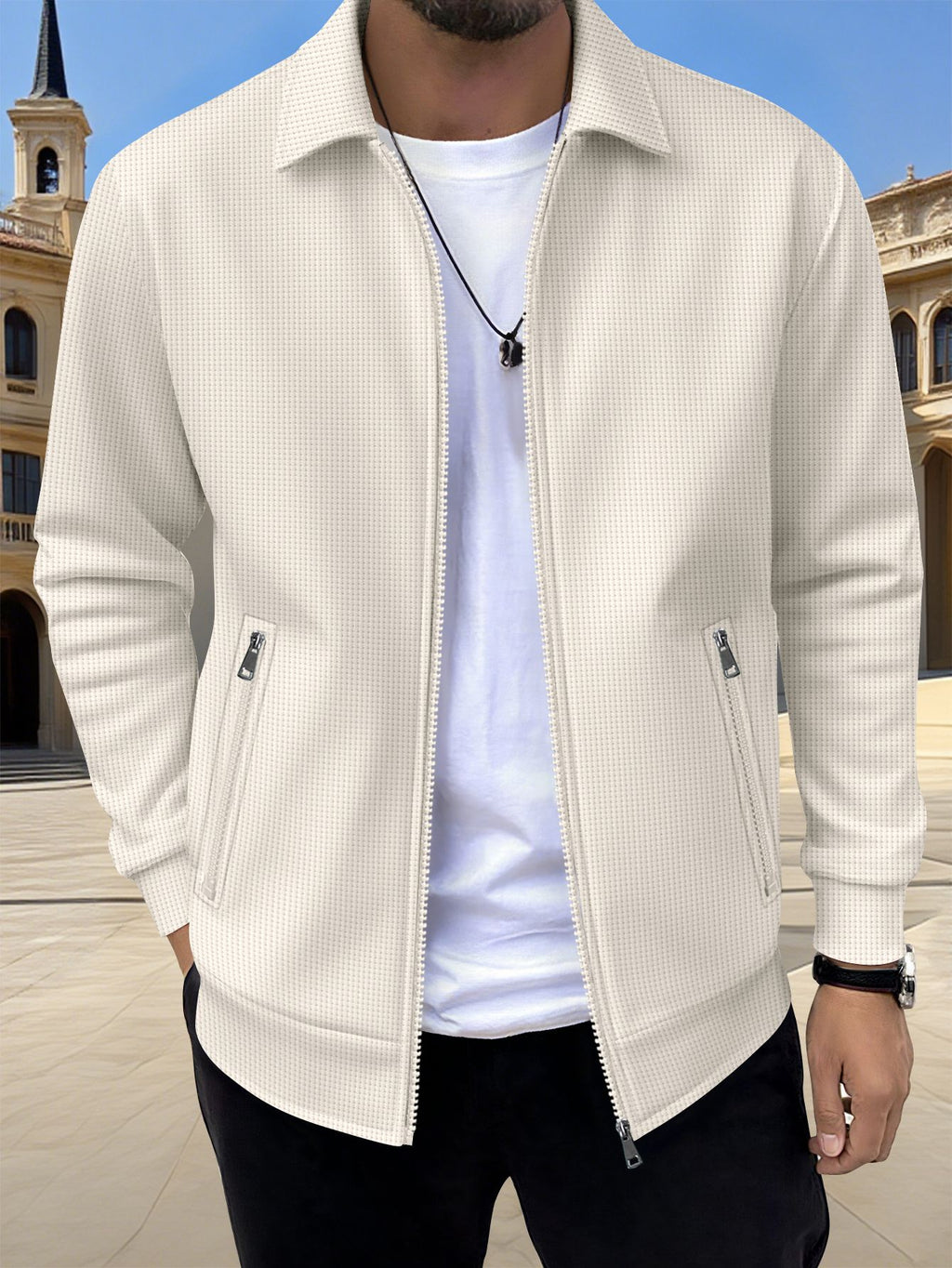 Man wearing a beige jacket over a white shirt with a blue sky background