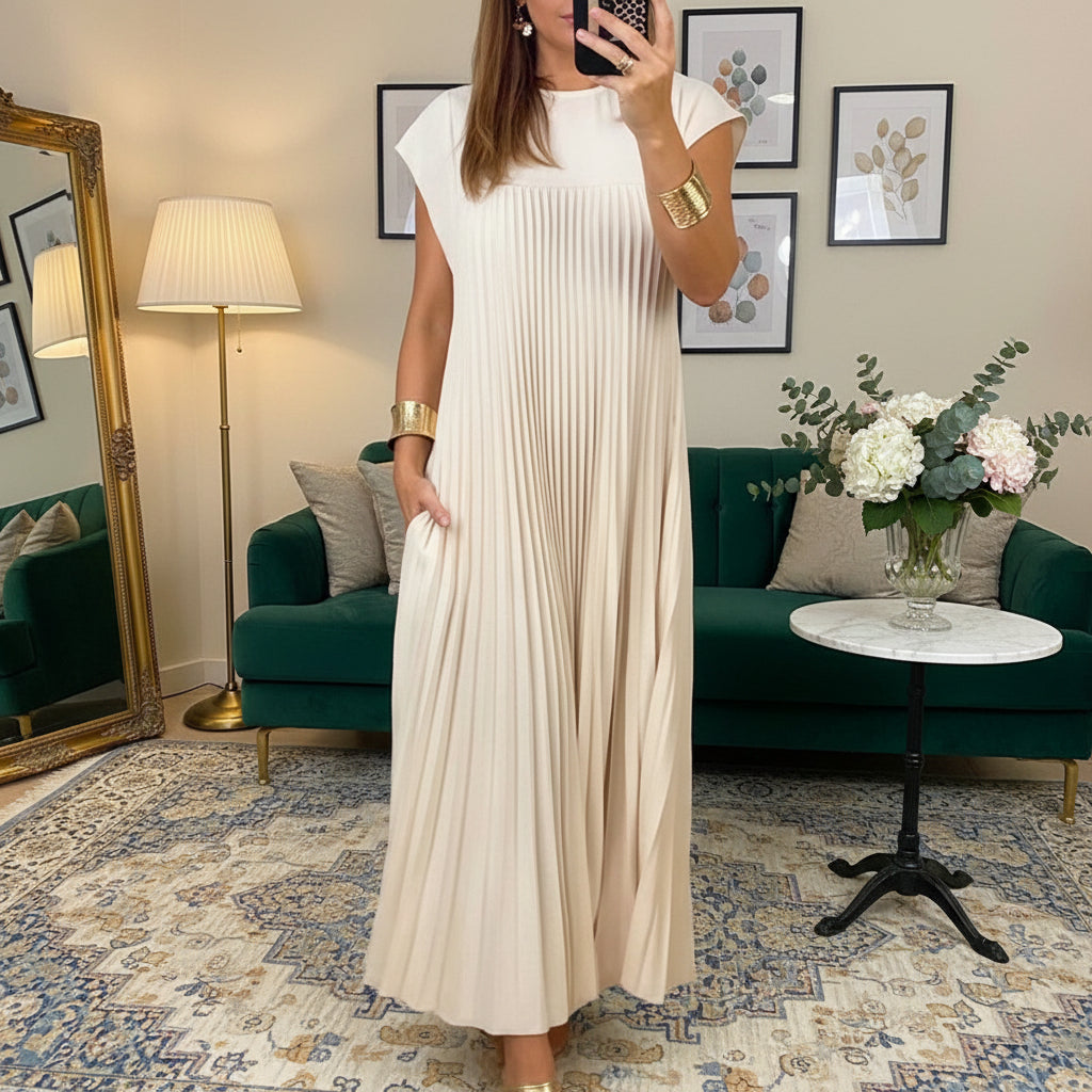 Woman wearing a long beige dress in a room with decor elements.