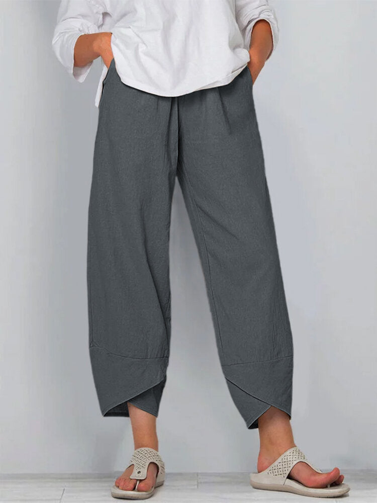 Person wearing gray wide-leg pants and a white shirt against a plain background
