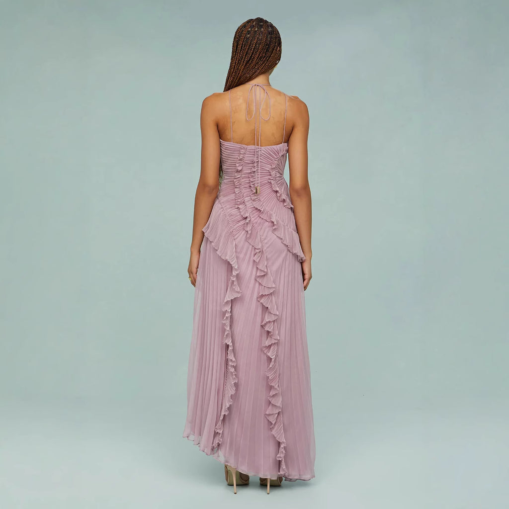 Woman wearing a long, ruffled pink dress on a light gray background