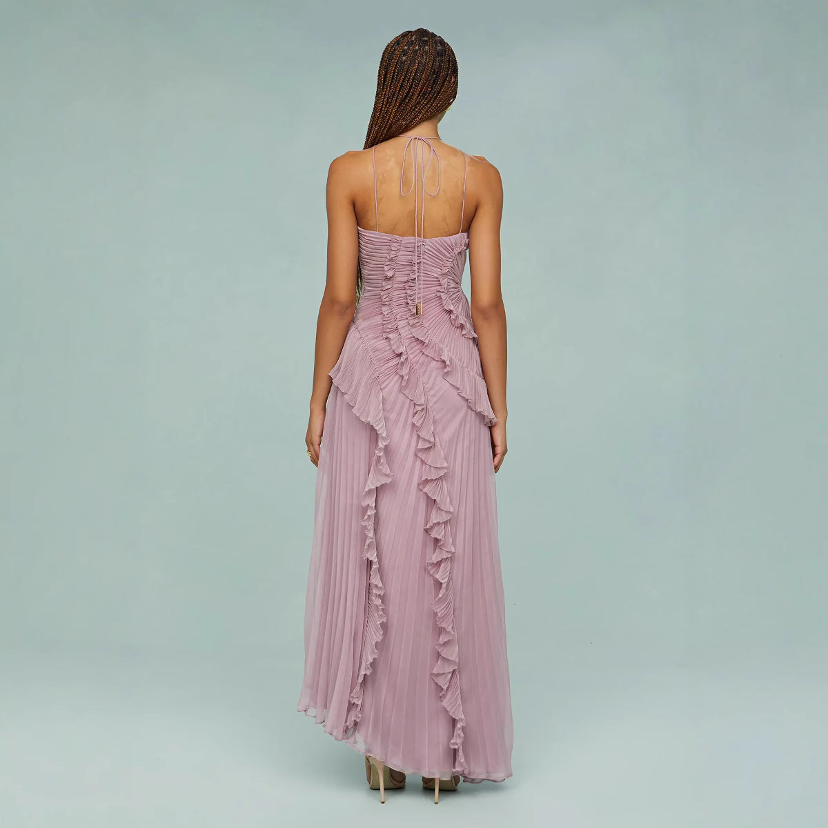 Woman wearing a long, ruffled pink dress on a light gray background