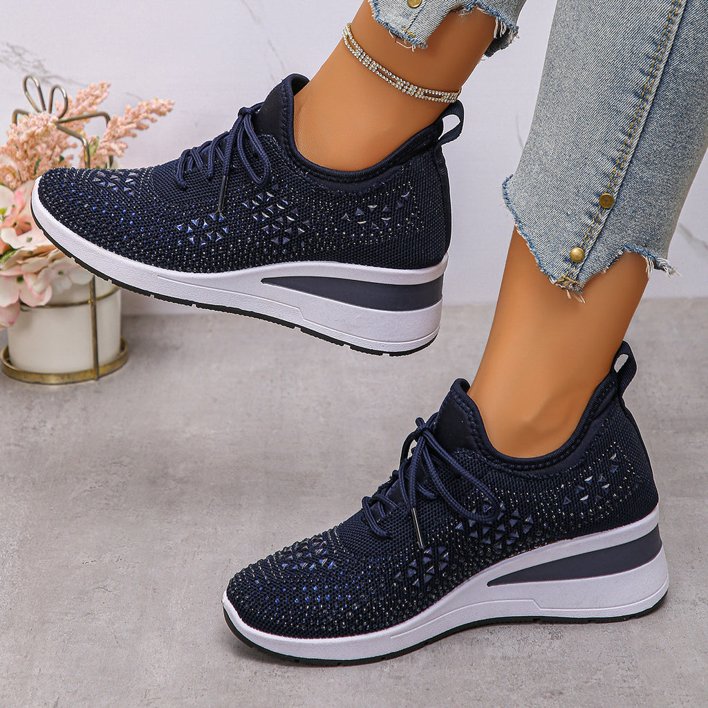 Navy blue athletic shoes with white soles worn by a person on a light gray surface.