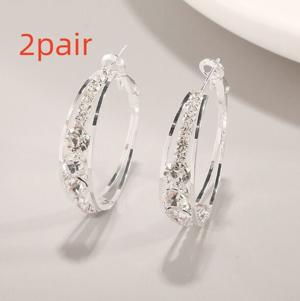 Pair of silver hoop earrings with clear gemstones on a light gray background