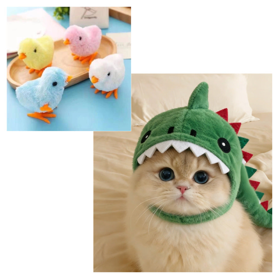 A fluffy cream-colored cat wearing a green plush dinosaur hat with white teeth and red spikes, shown in a bedroom setting. A smaller inset shows three small plush bird toys in yellow, pink, blue, and white on a wooden tray.