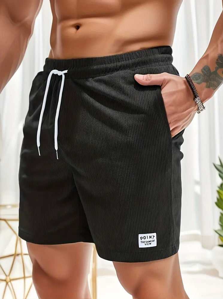 Person wearing black shorts with a brand logo, standing indoors.