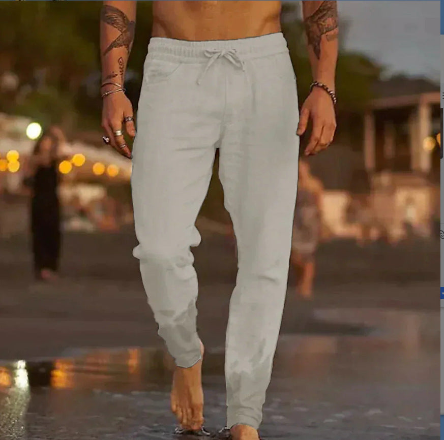 A man walking barefoot outdoors at dusk wearing light gray jogger sweatpants with a drawstring waistband.