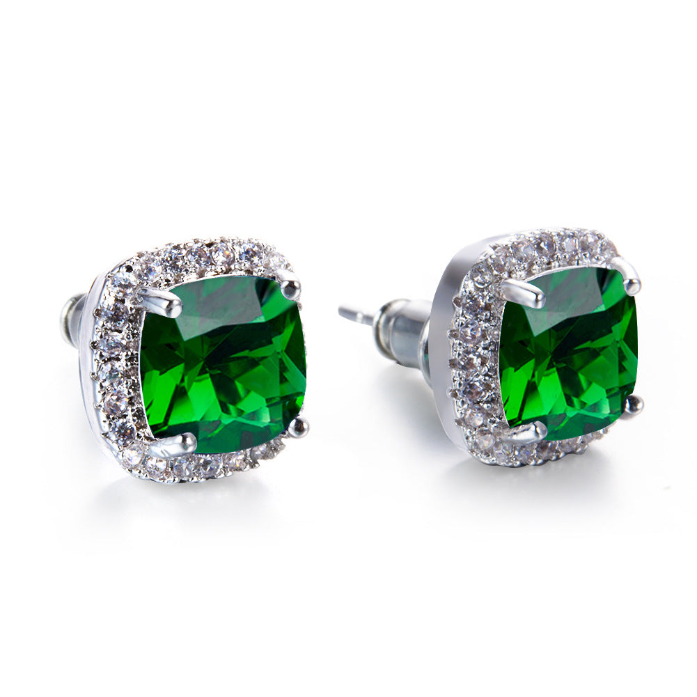 Pair of green gemstone earrings with silver settings on a white background
