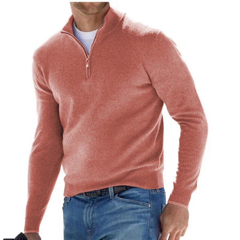 Man wearing a pink quarter-zip sweater and blue jeans on a white background