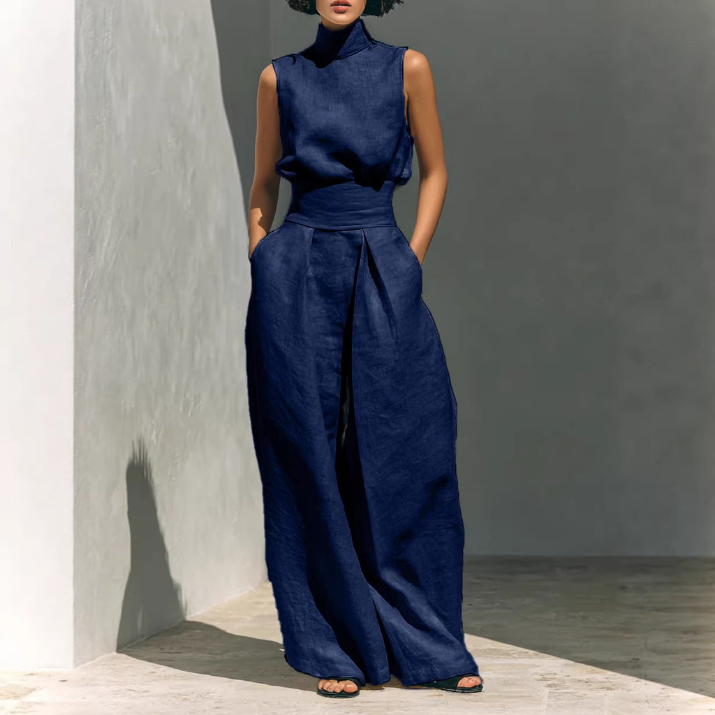 Person wearing a blue outfit standing against a gray wall.