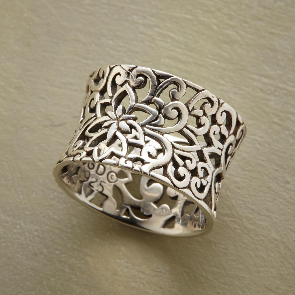 Silver filigree ring on a beige background