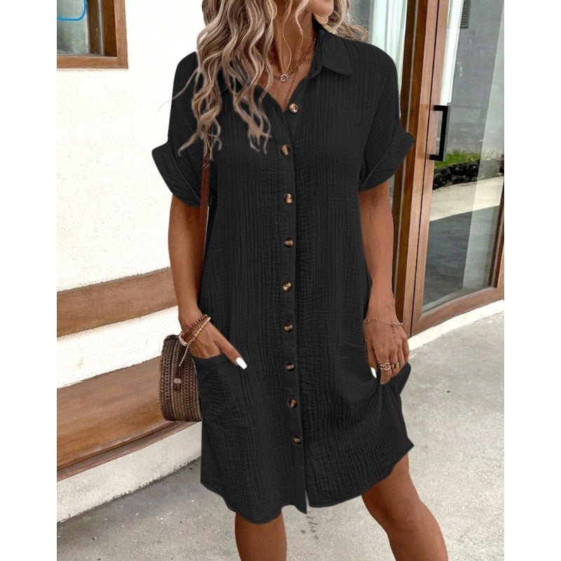 Woman wearing a black button-up dress standing outdoors.