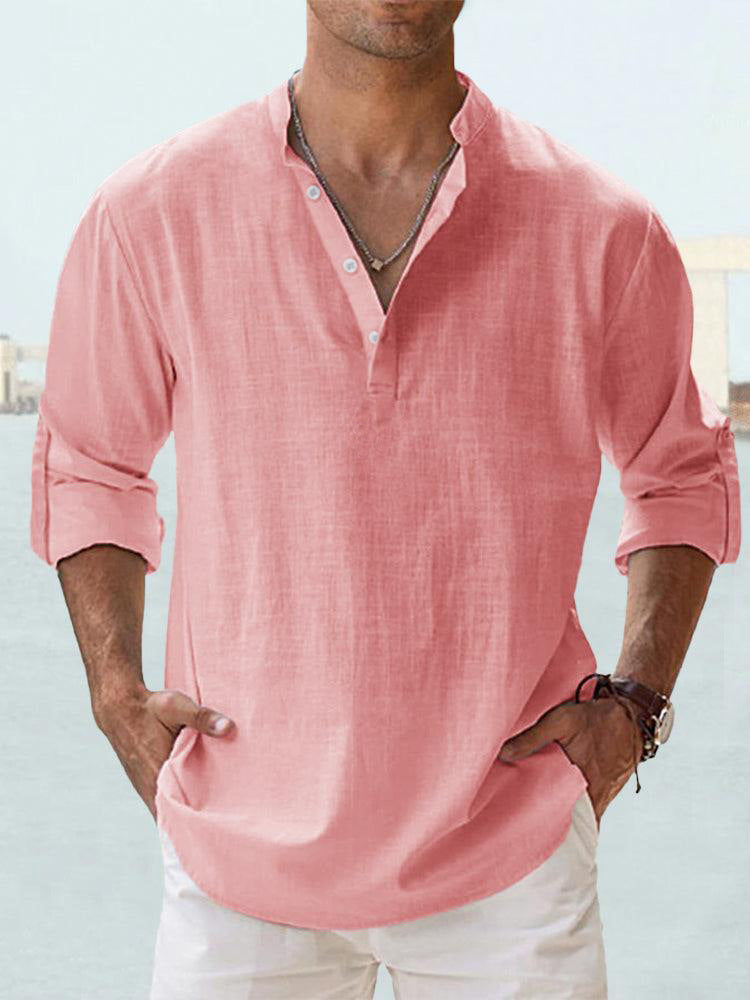 Man wearing a pink shirt with rolled-up sleeves against a blurred background