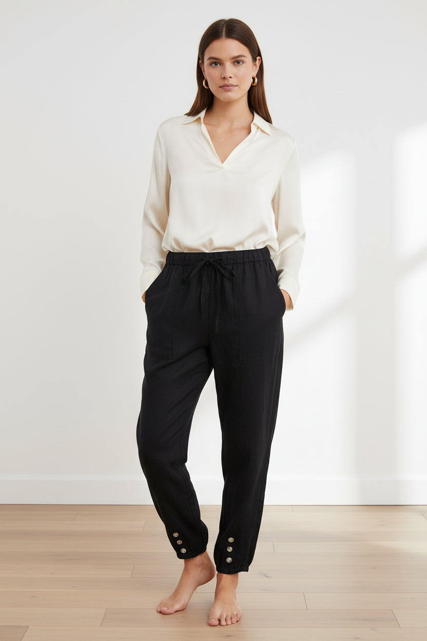 Black pants with button details worn by models on a light wooden floor.