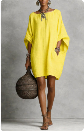 Woman wearing a yellow dress holding a woven bag against a gray background