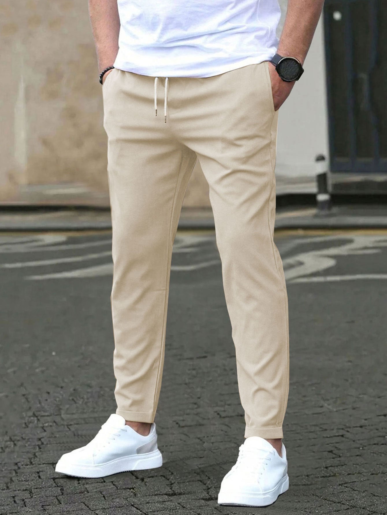 Person wearing beige pants and white sneakers on a street.