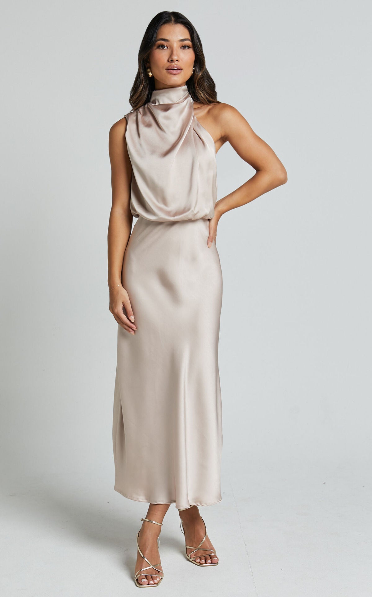 Woman wearing a beige satin dress against a plain background
