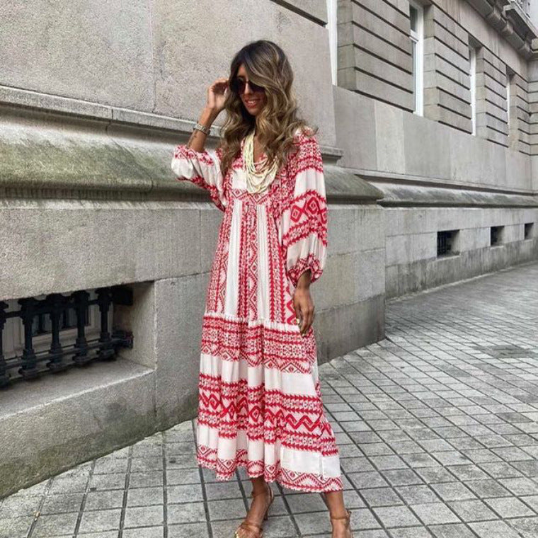 Woman wearing a red and white patterned dress standing against a stone wall.