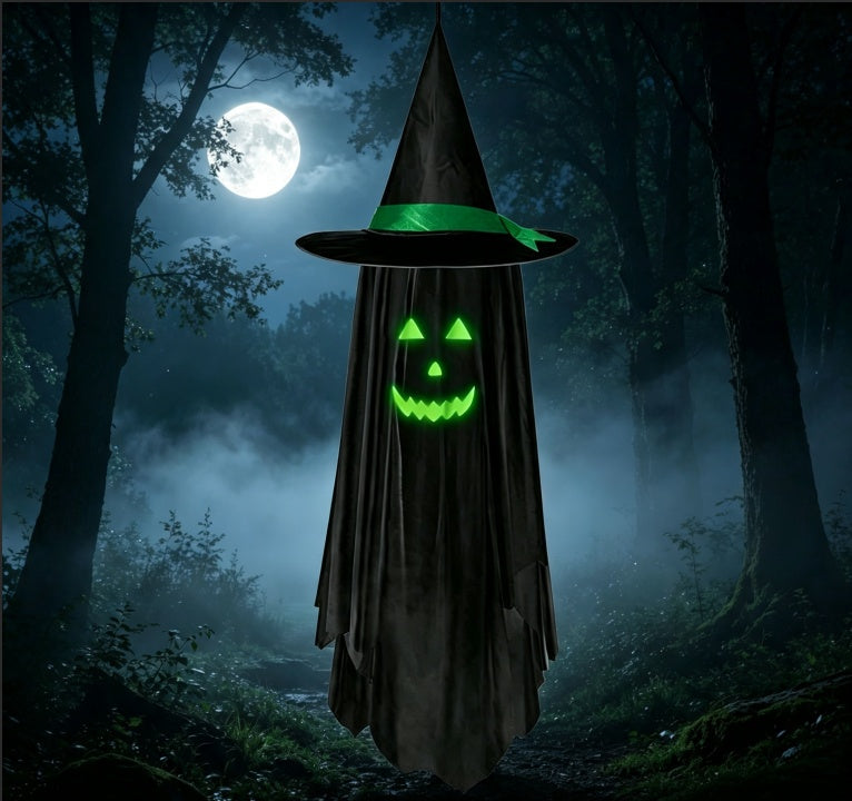A Halloween ghostly figure wearing a tall black witch hat with a green band and a tattered black cloak, standing in a misty dark forest at night with a glowing jack-o'-lantern face and a full moon in the background.