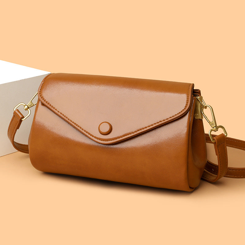 Brown leather handbag with gold accents on a beige background