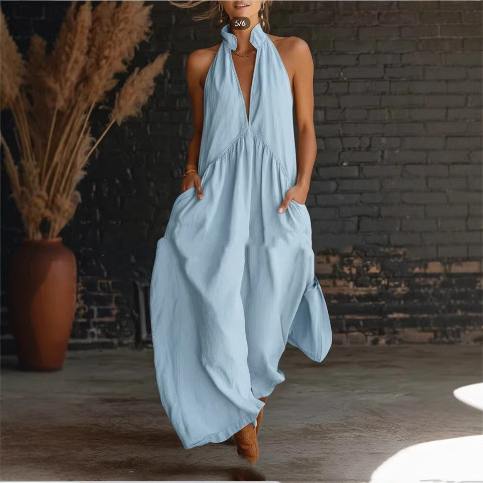 Woman wearing a light blue halter neck dress against a brick wall.