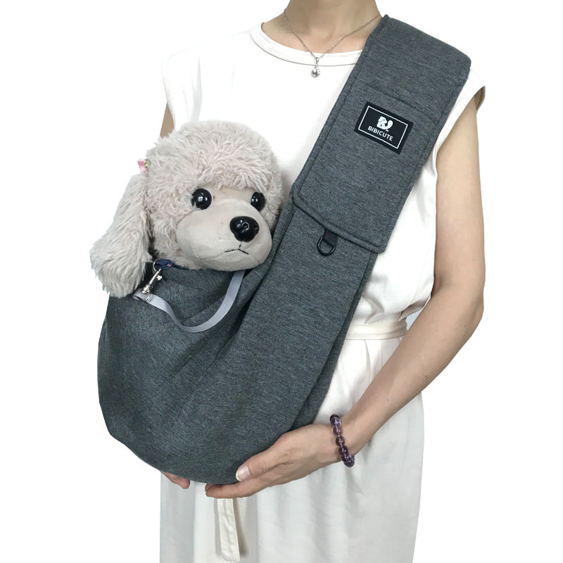 Person holding a gray pet sling with a small dog inside on a white background