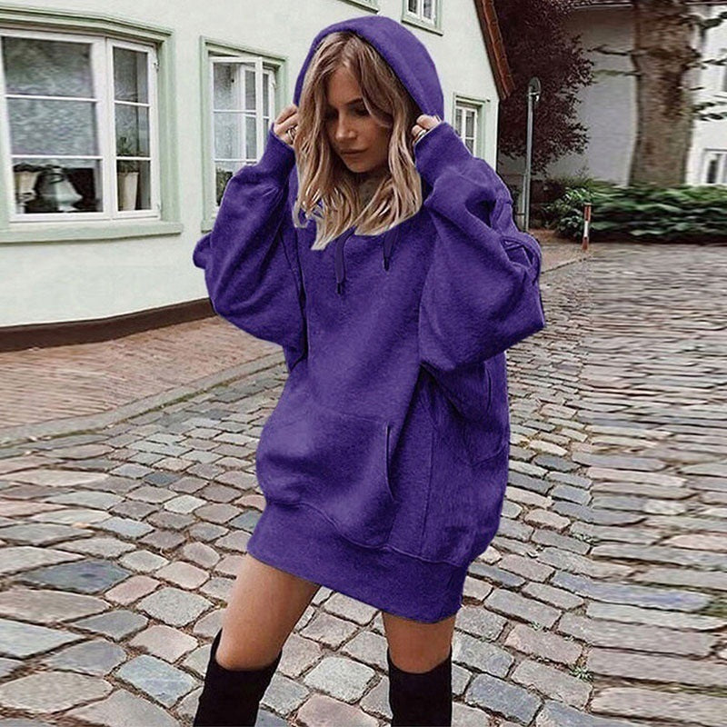 Person wearing a purple hoodie dress on a cobblestone street.